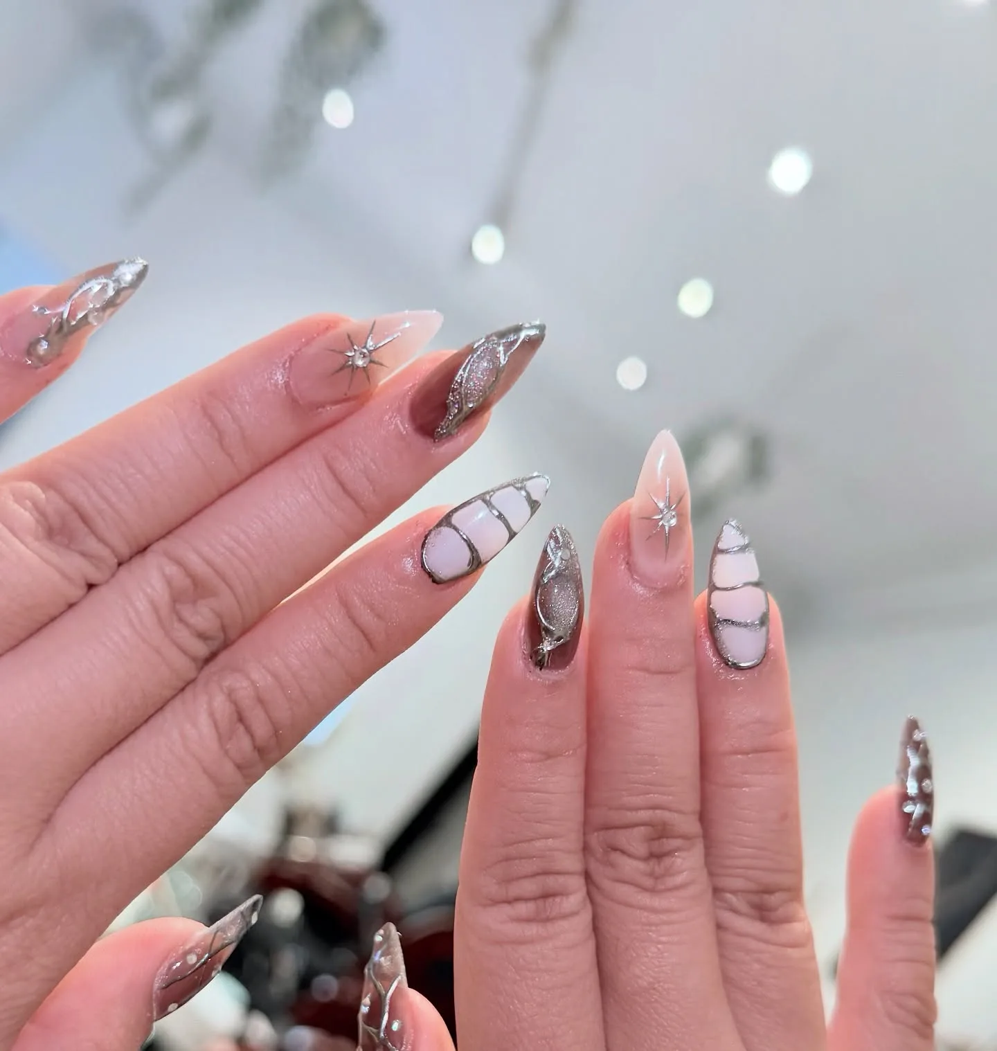 Milky chrome swirl nails with silver starburst accents