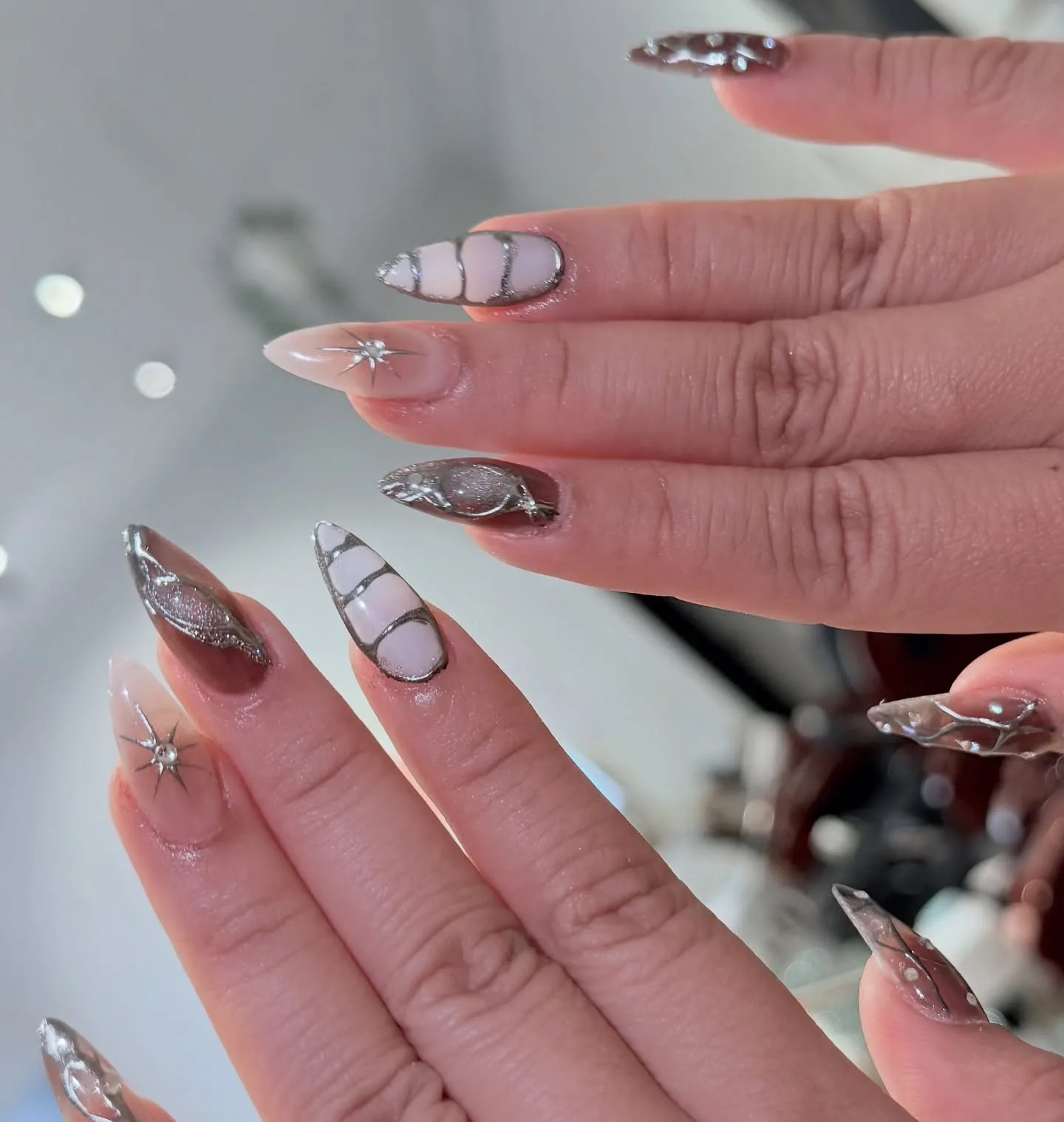 Nude chrome and silver starburst almond nails