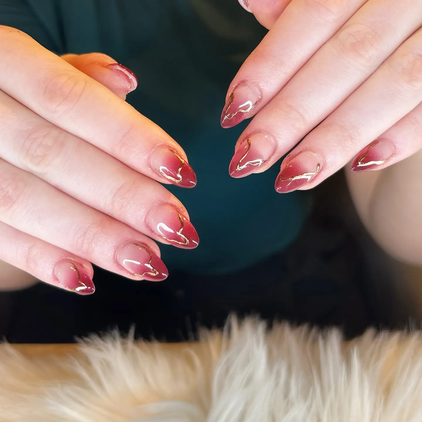 Red to nude ombre almond nails with gold swirl detailing