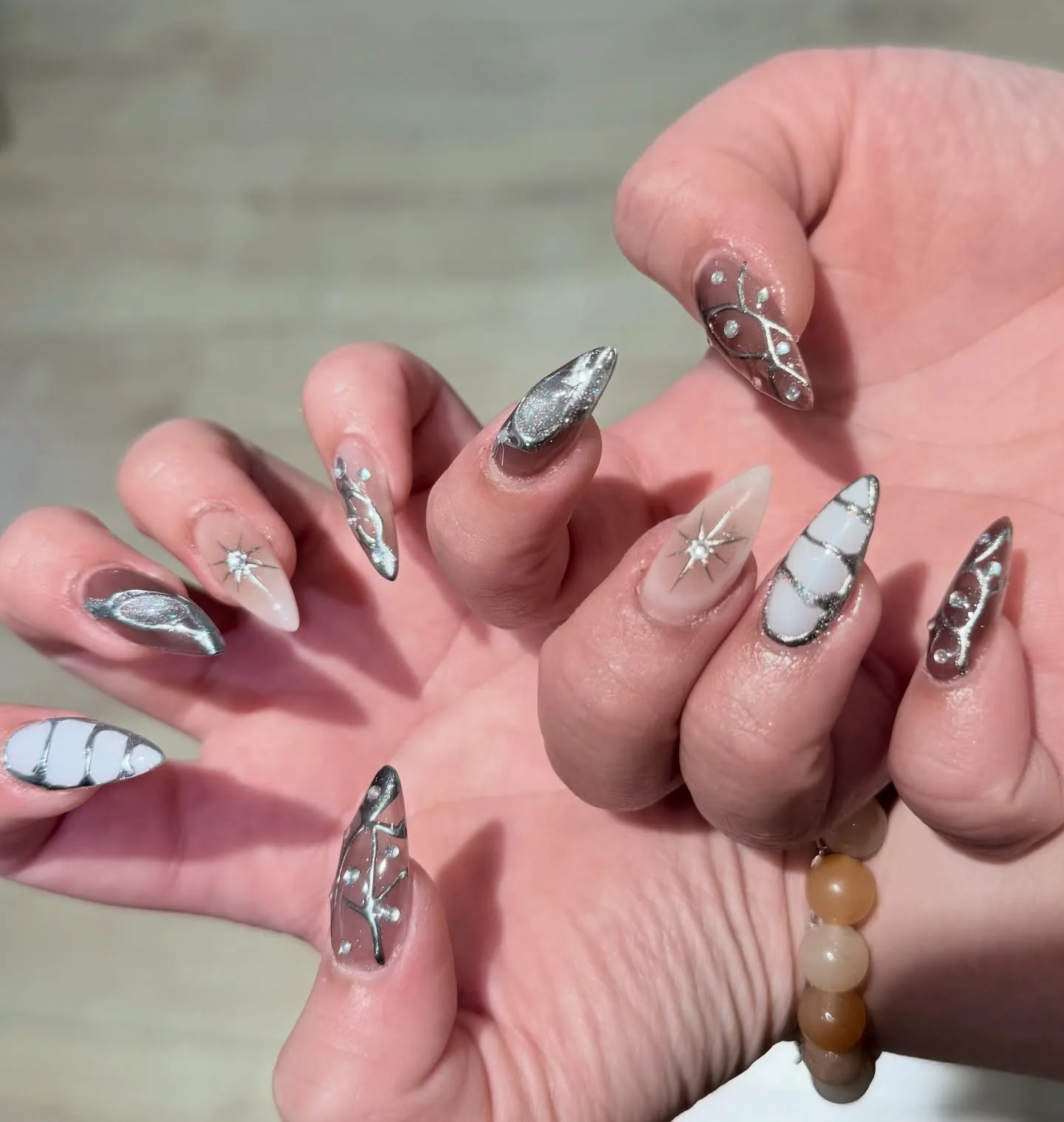 Silver chrome stiletto nails with starburst accents